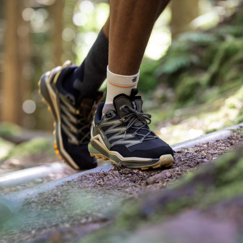 A close-up outdoor shot of a person hiking in a forest, wearing their Bauerfeind Sport Outdoor Ankle Compression Sleeve.