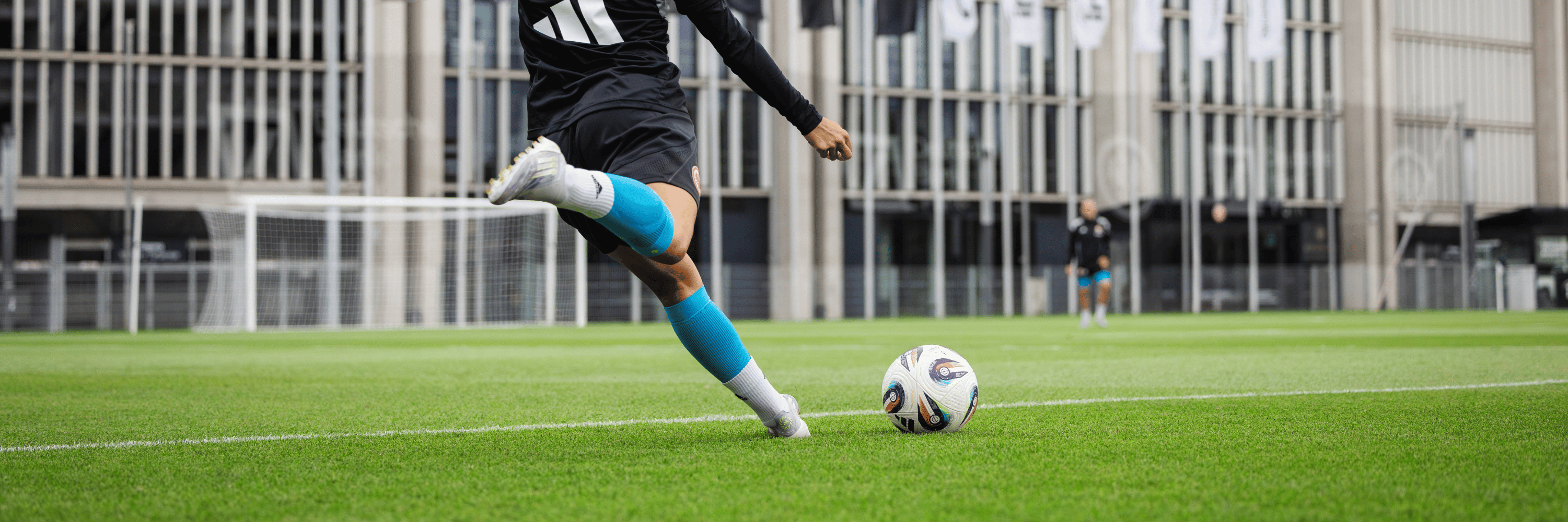 man wearing bauerfeind sports compression calf sleeves kicking a soccer ball