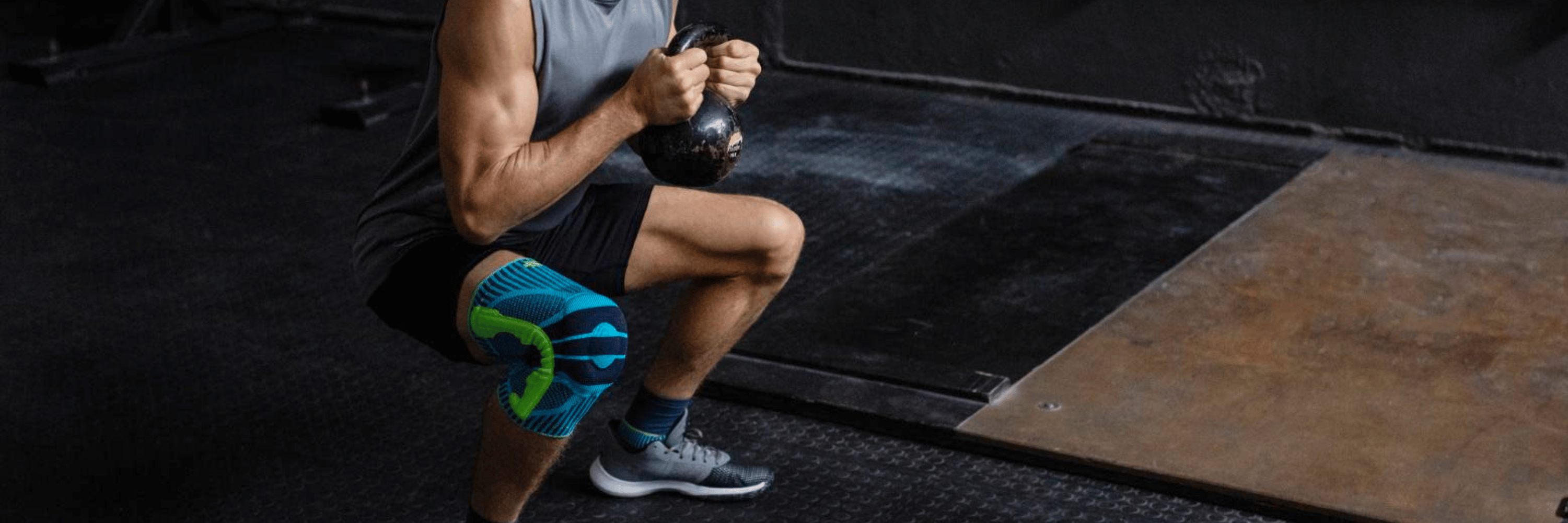 Person exercising with a kettleball in a gym setting wear the Bauerfeind Sports Knee Support.