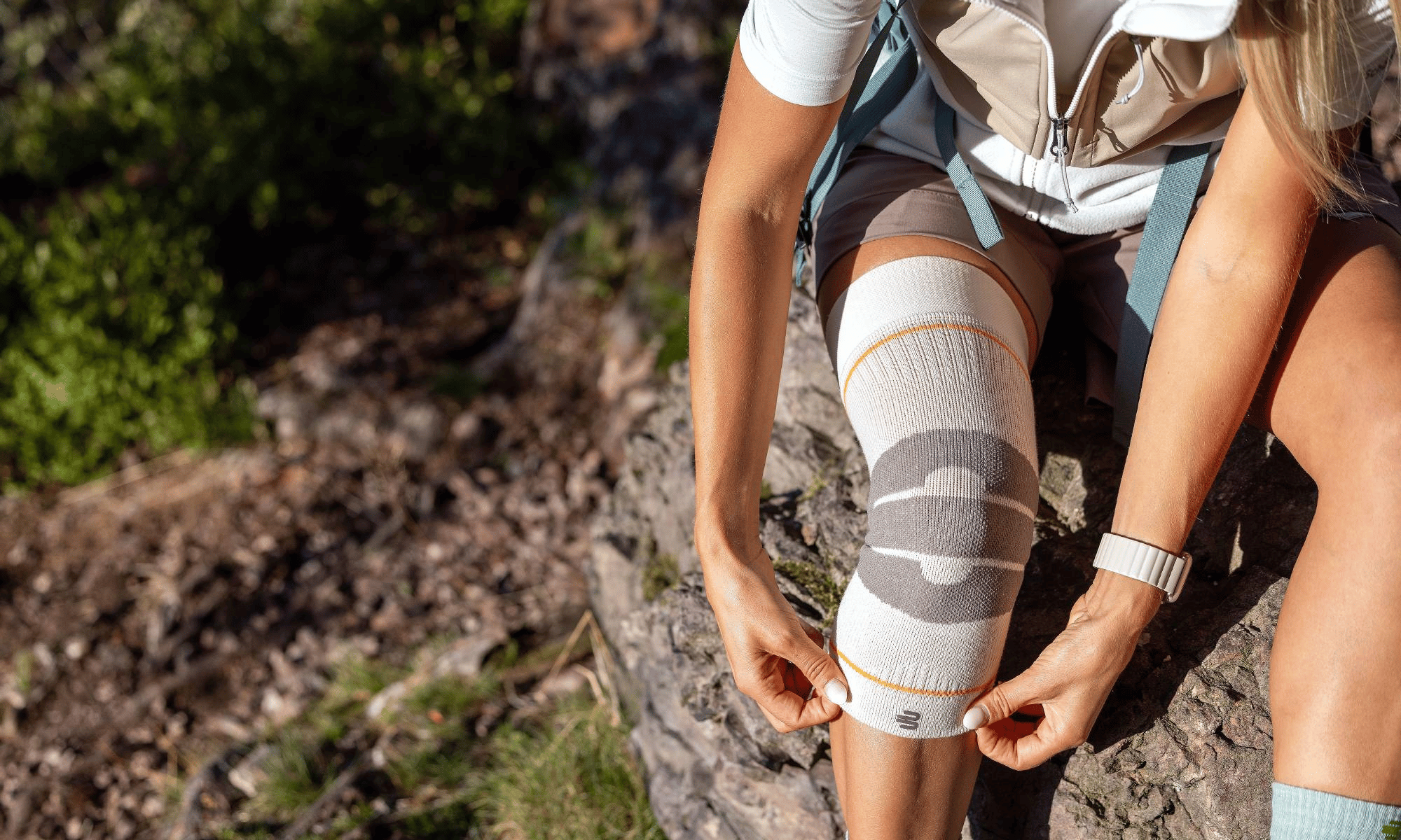 Person hiking on a rocky trail wearing a Bauerfeind's outdoor compression knee brace.