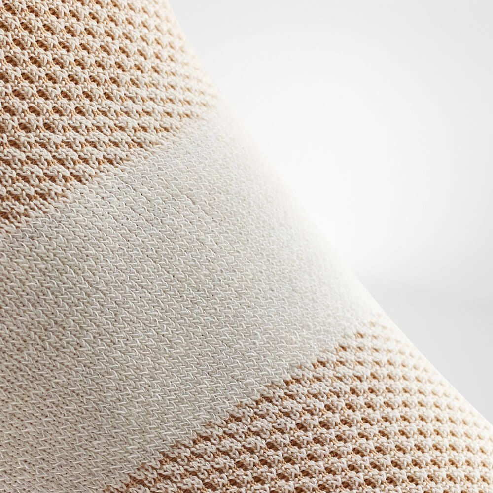 Close-up of beige fabric with a textured pattern on a light gray background