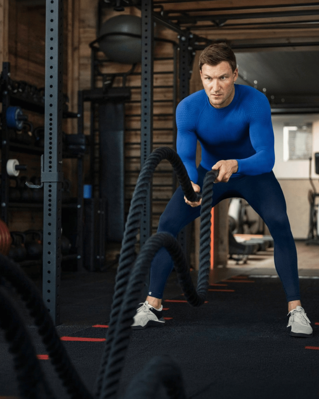 Man in bauerfeind sports compression wear using battle ropes in a gym setting