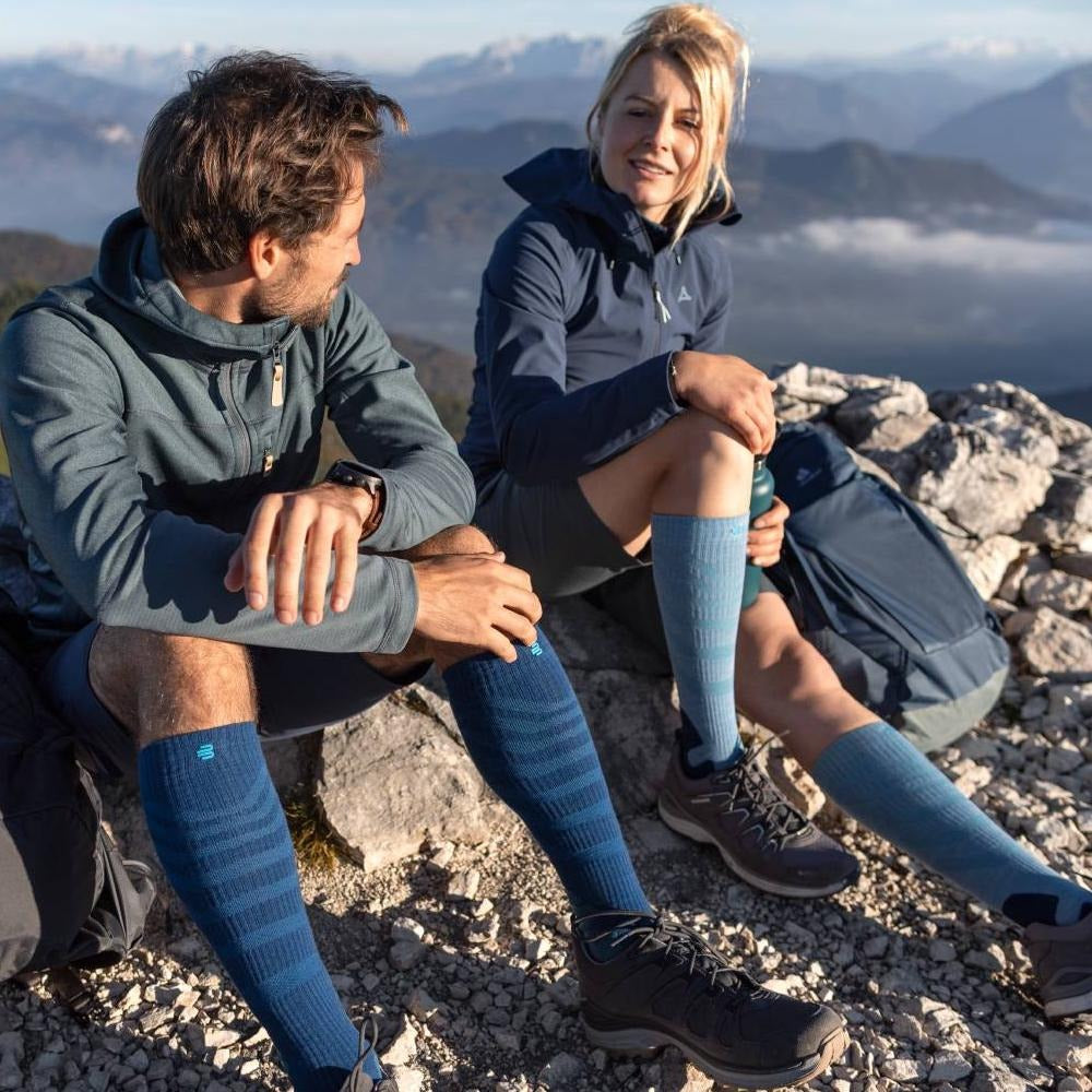 Two people sitting on a mountain top wearing blue knee-high socks.