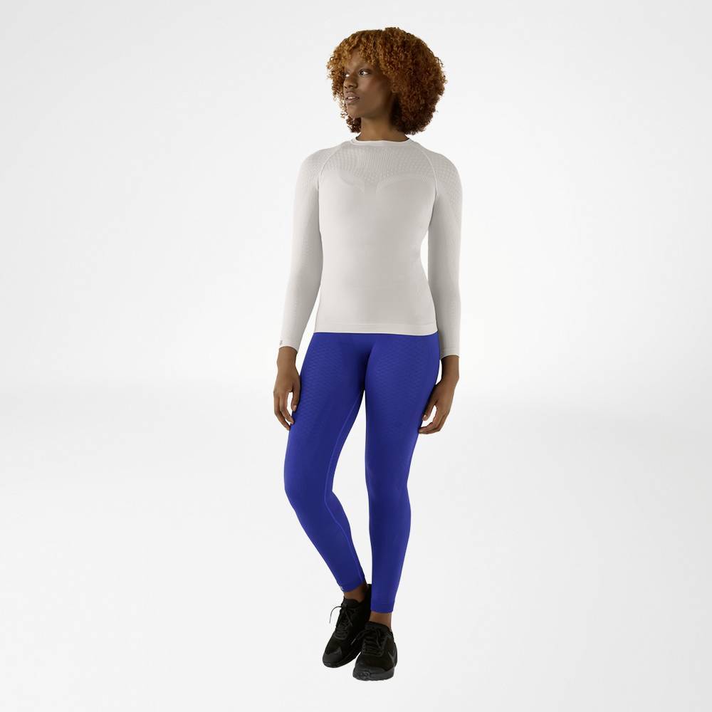 Person wearing a silver long-sleeve bauerfeind compression shirt and blue compression leggings on a light gray background