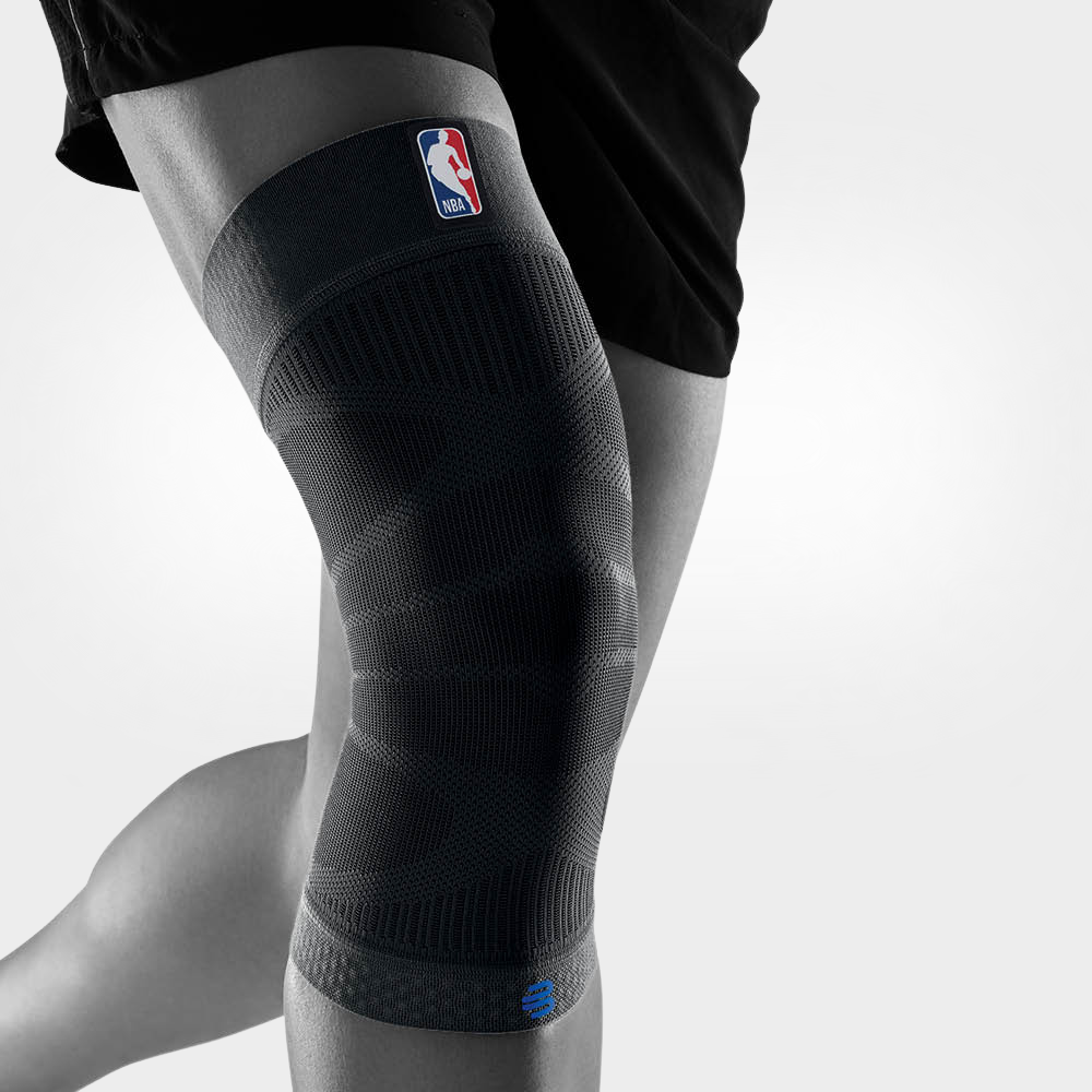 A person wearing a black bauerfeind Sports Compression Knee Support NBA