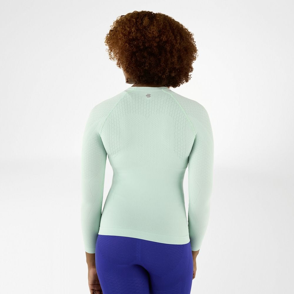 woman wearing a mint green long-sleeve bauerfeind compression shirt and blue compression leggings on a white background
