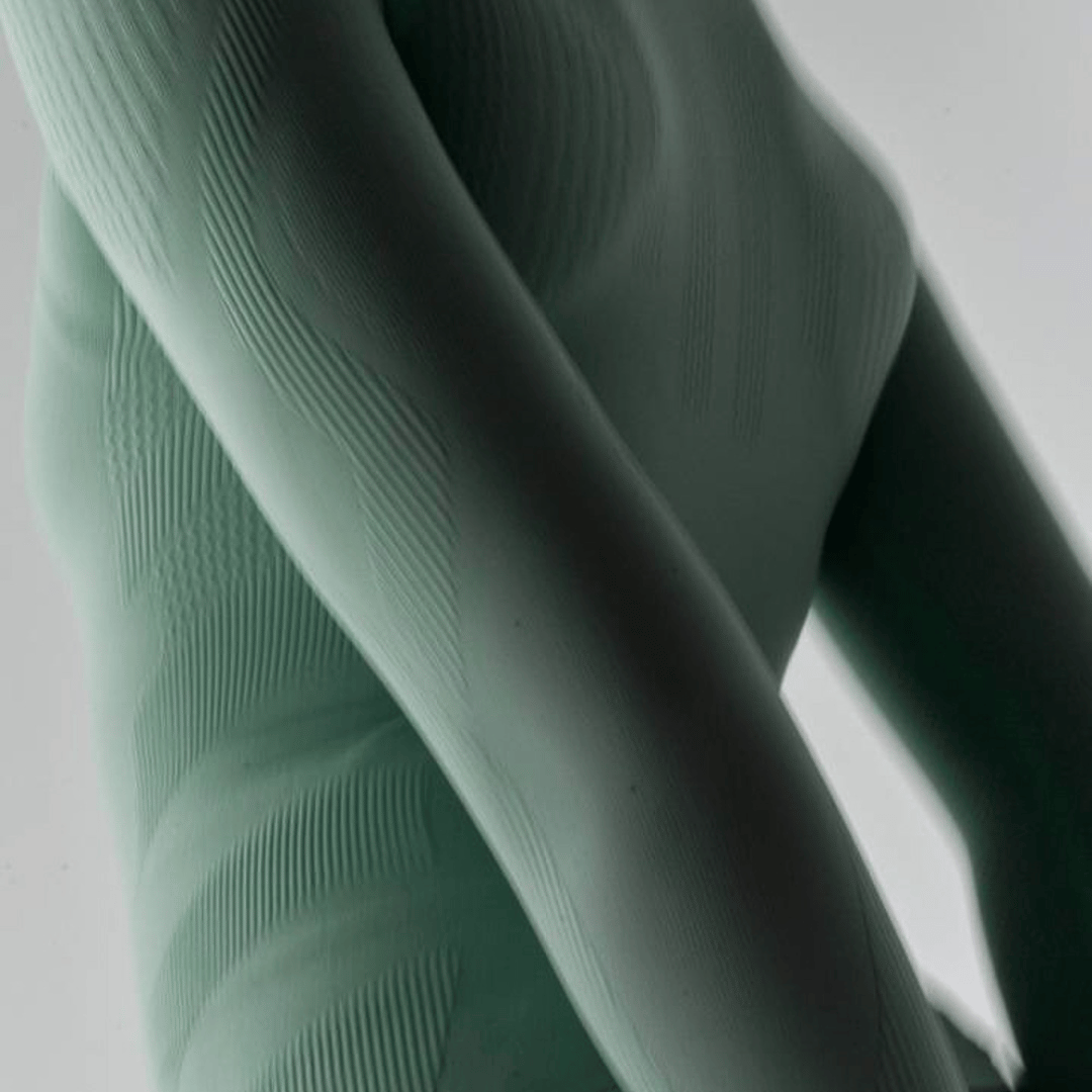 Close-up of textured fabric of the mint bauerfeind sports compression short-sleeve shirt on a light gray background