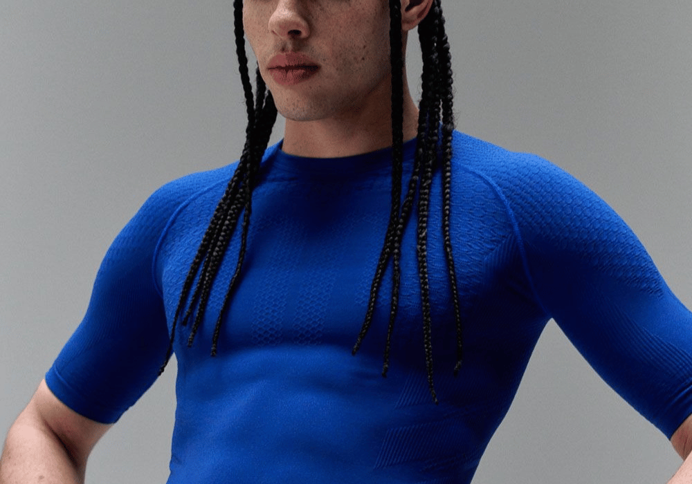Person wearing a blue bauerfeind sports compression shirt against a gray background