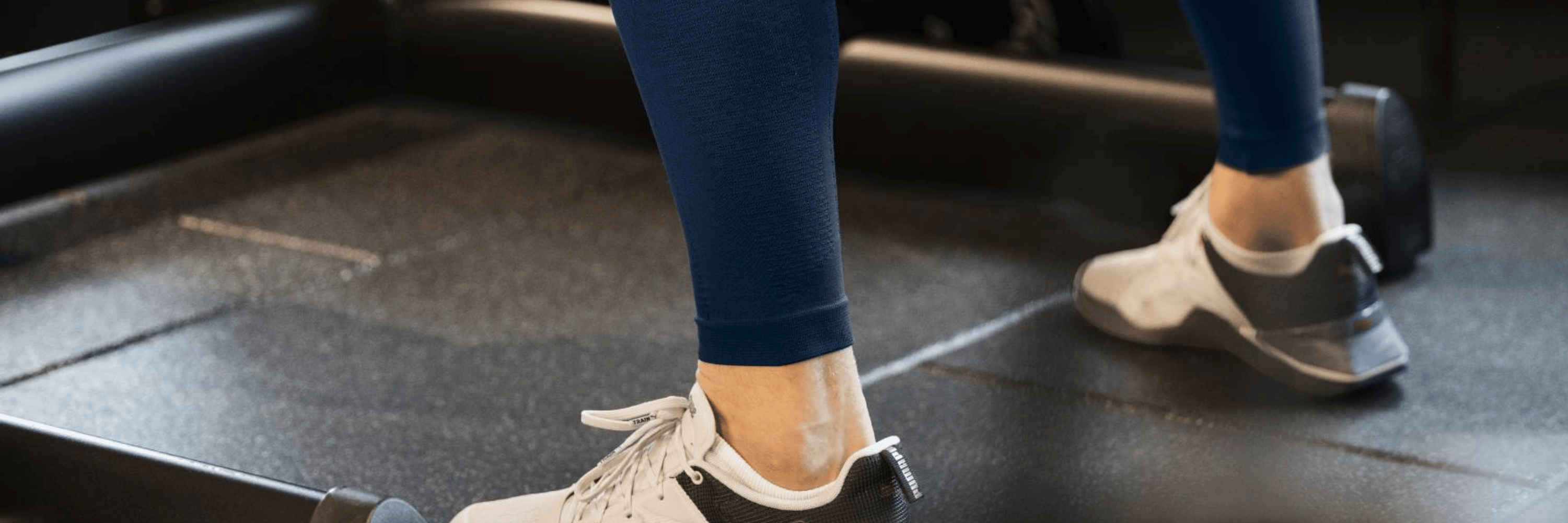 Person lifting weights wearing navy bauerfeind sports compression tights