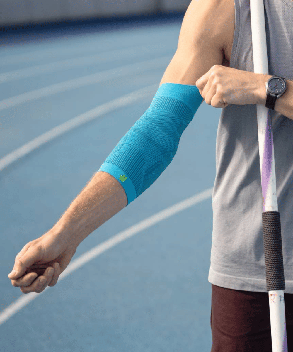 Person on a tennis court wearing a blue arm sleeve.