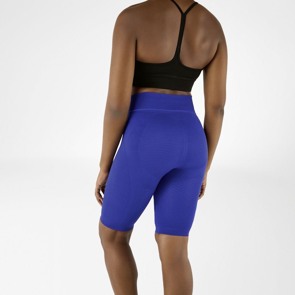 Person wearing blue athletic Bauerfeind Women's sport compression shorts and black sports bra on a white background