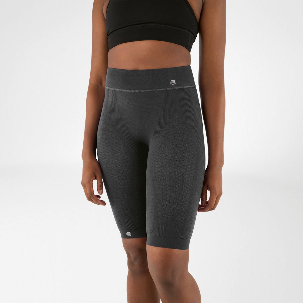 Person wearing gray athletic Bauerfeind Women's sport compression shorts and black sports bra on a white background