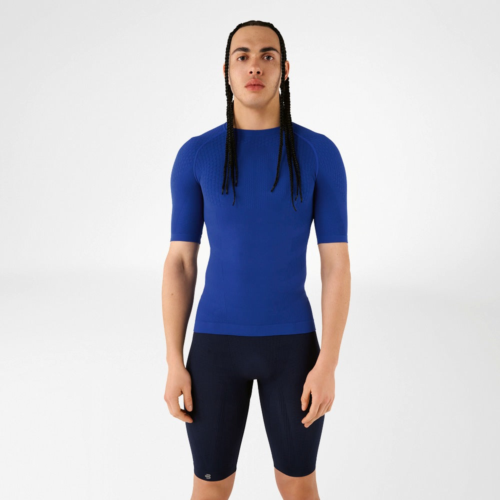 Person wearing blue athletic Bauerfeind men's Sports Compression Short Sleeve Shirt and Navy blue Bauerfeind's Men Sport compression shorts on a white background