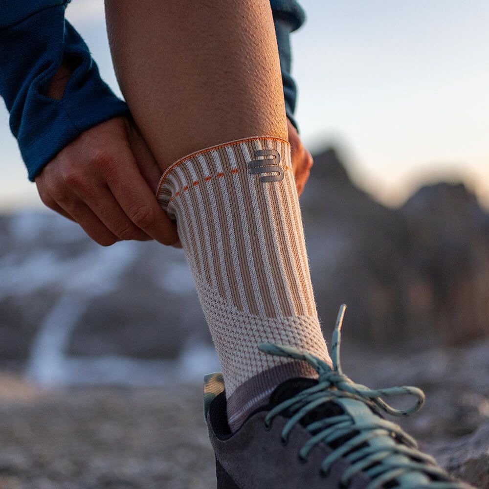 Person wearing an ankle support with a bauerfeind logo, standing on a rocky surface.