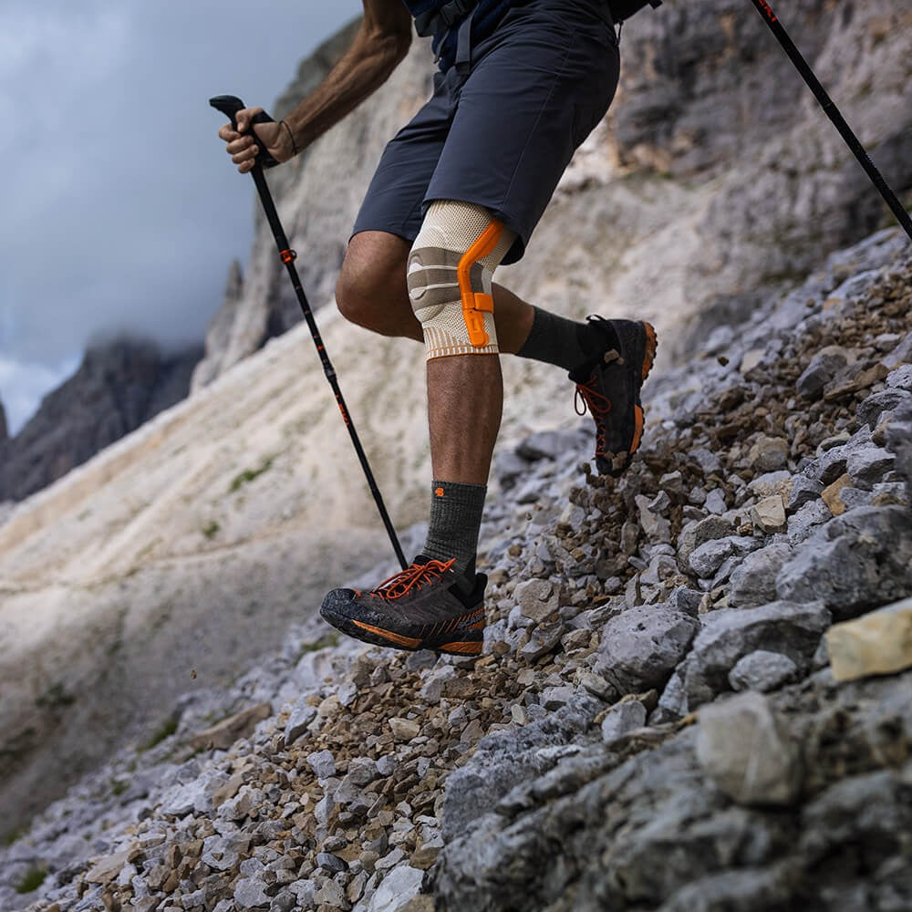 Person hiking on a rocky mountain trail with knee brace