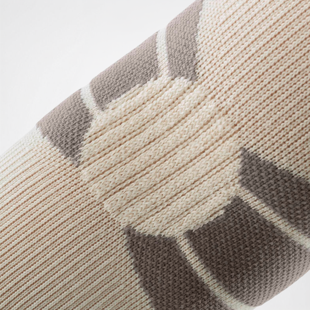 Close-up of a ribbed knit Bauerfeind Sport Outdoor Elbow Compression Sleeve on a light gray background.