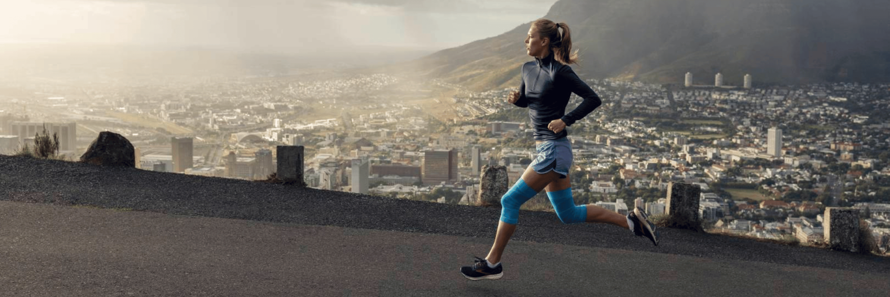 Person running on a road with a cityscape and mountain in the background