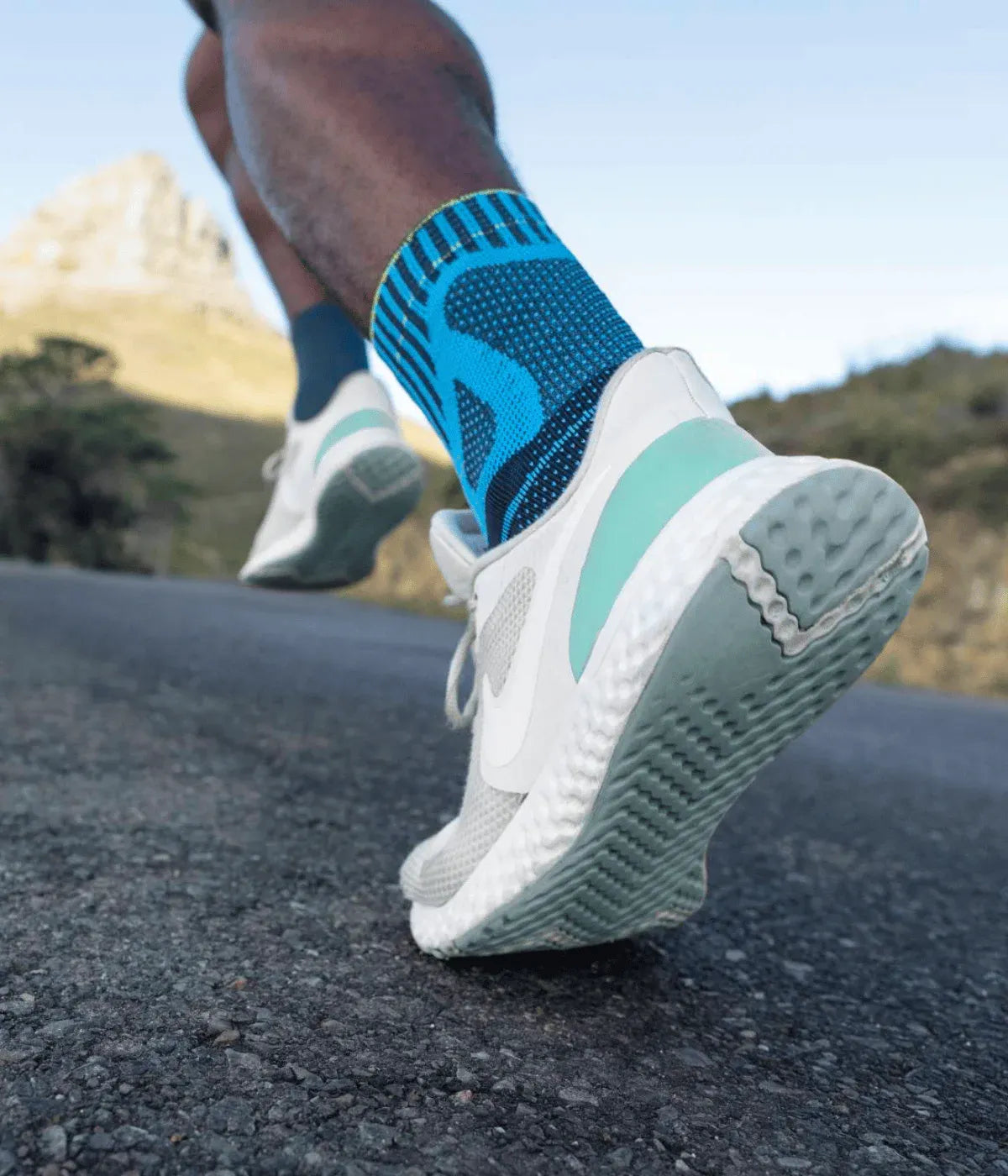 Person running on a road with blue and white running shoes