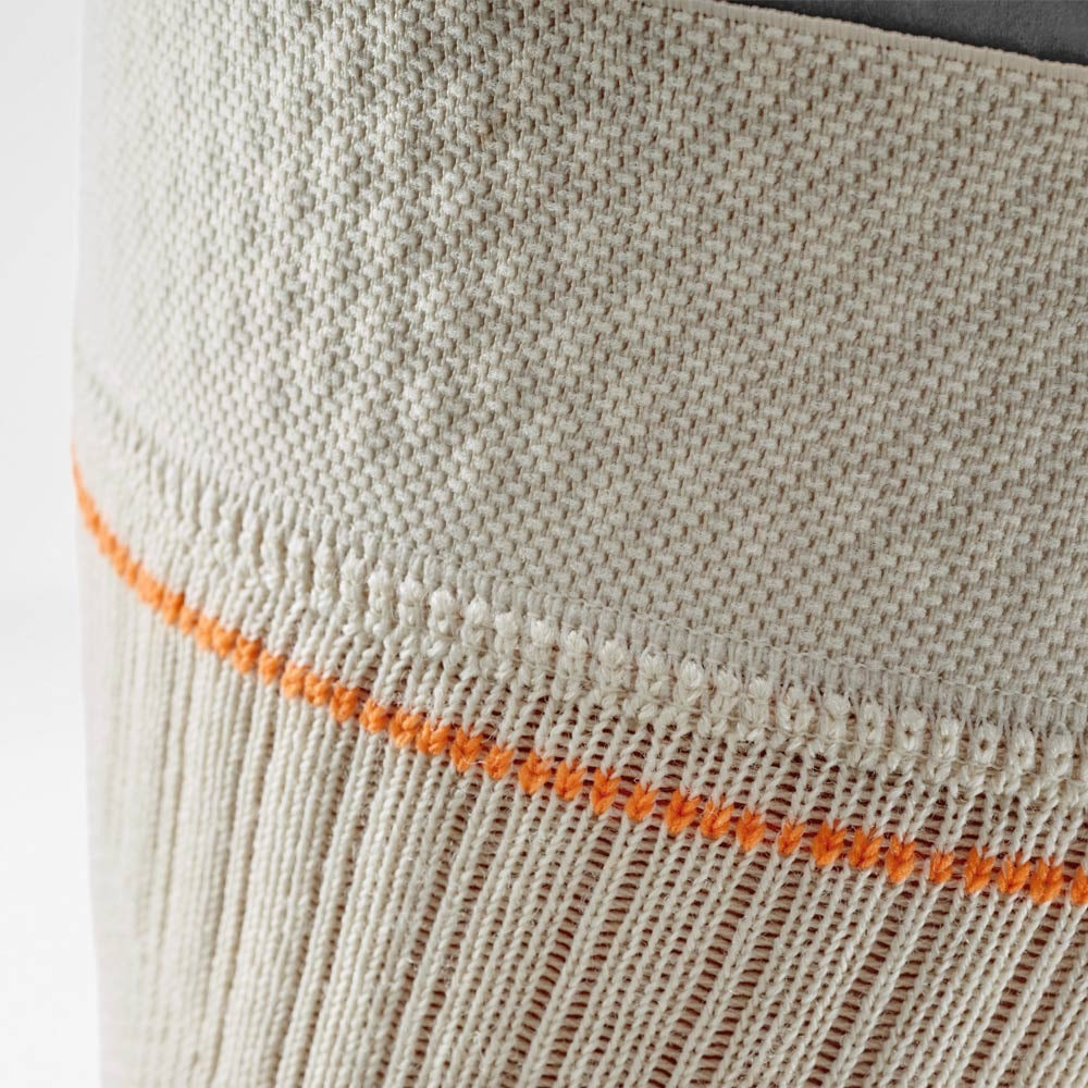 Close-up of beige knee sleeve with orange stitching detail
