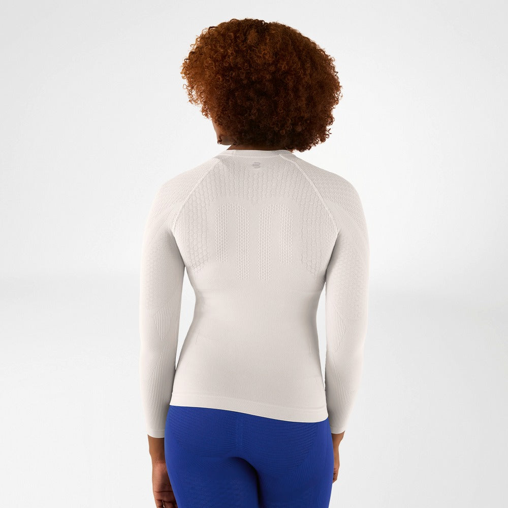 Person wearing a wsilver bauerfeind compression long-sleeve athletic top and blue compression leggings on a light gray background