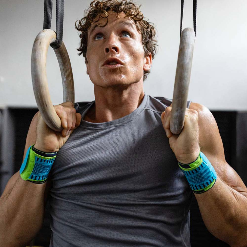 Man exercising on rings with a focused expression wearing bauerfeind Sports Wrist Straps