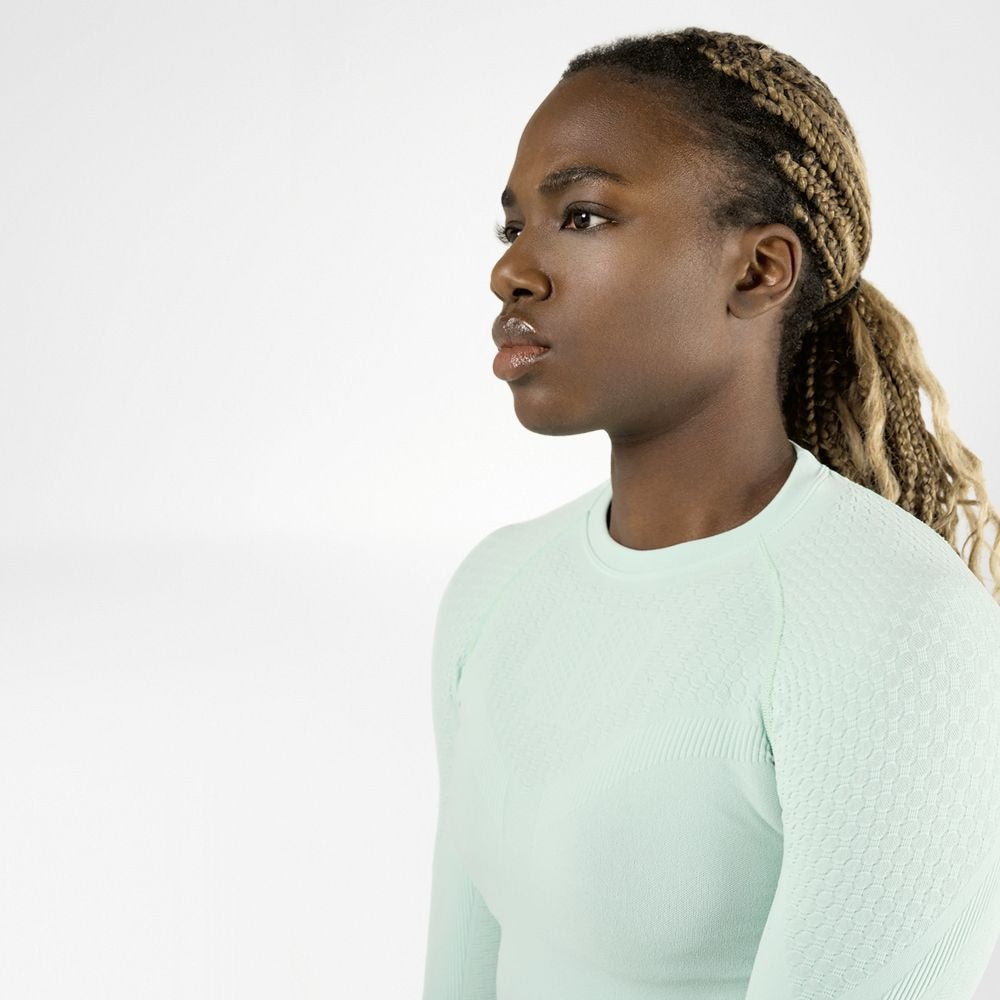Woman wearing a mint green compression shirt against a white background