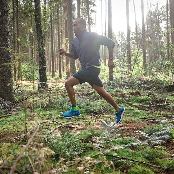 Person running through a forest wearing bauerfeind sport ankles support