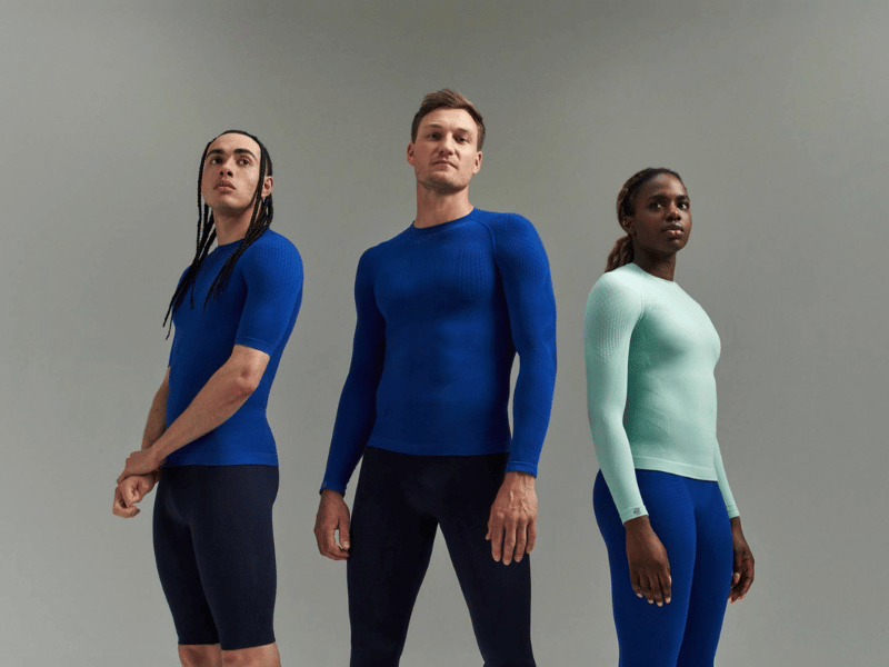Three people wearing the Bauerfeind Sport Compression Wear Collection, on a grey background