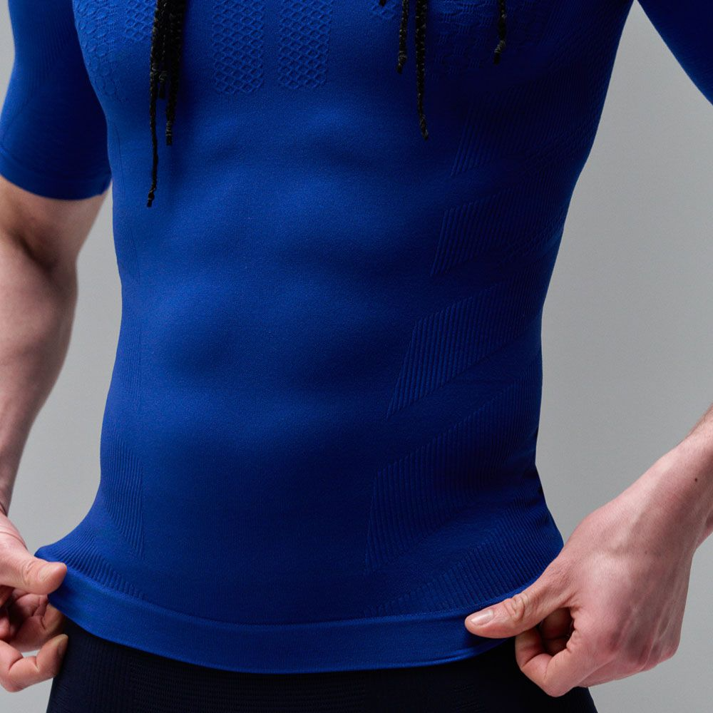 Person wearing a blue Bauerfeind sport compression short-sleeve shirt against a gray background