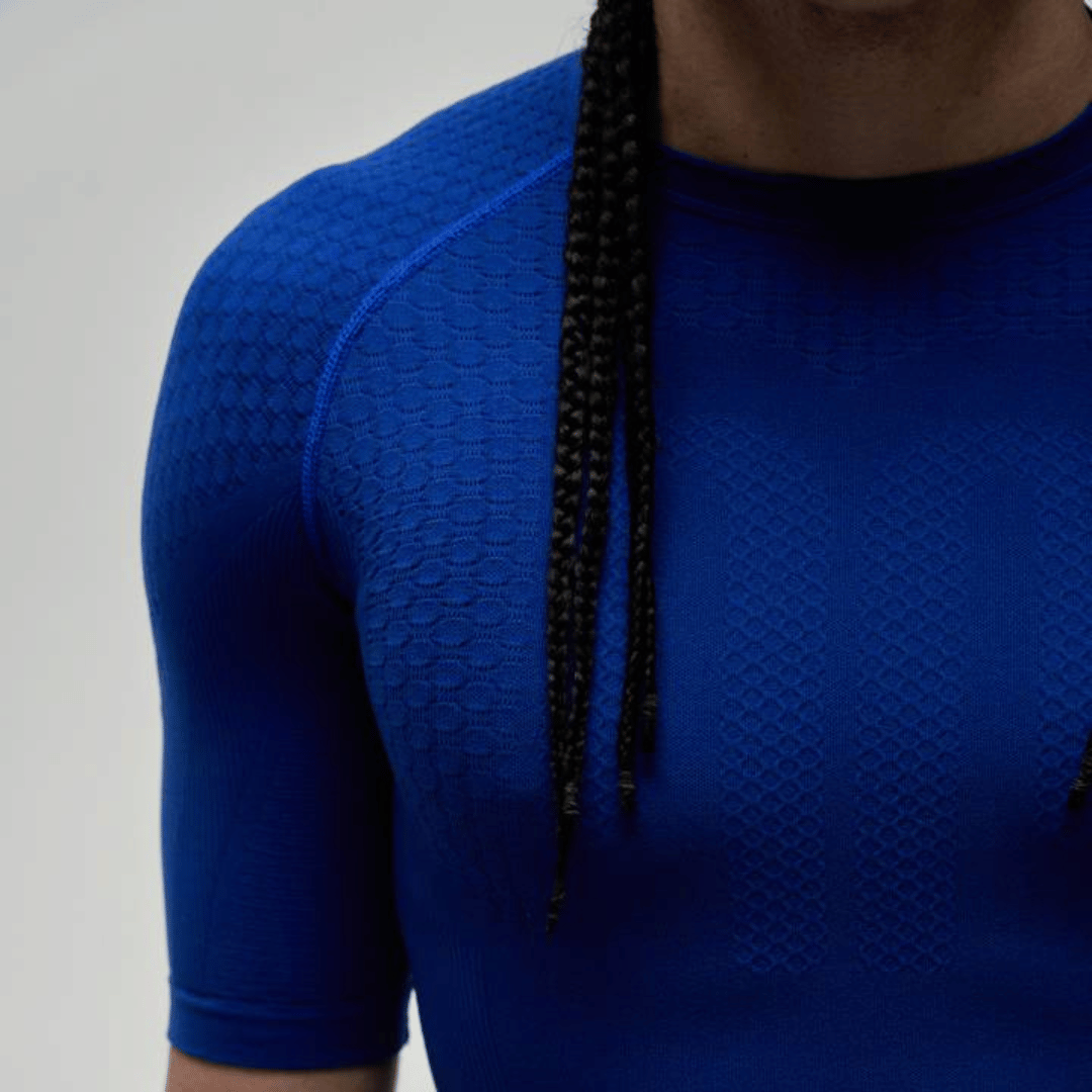 Close-up of textured fabric of the blue bauerfeind sports compression short-sleeve shirt on a light gray background