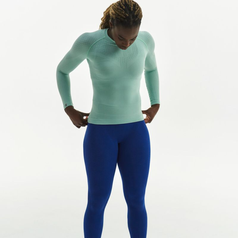 Person wearing a mint green Bauerfeind Sport Compression long-sleeve top and blue Bauerfeind Sport Compression leggings on a white background
