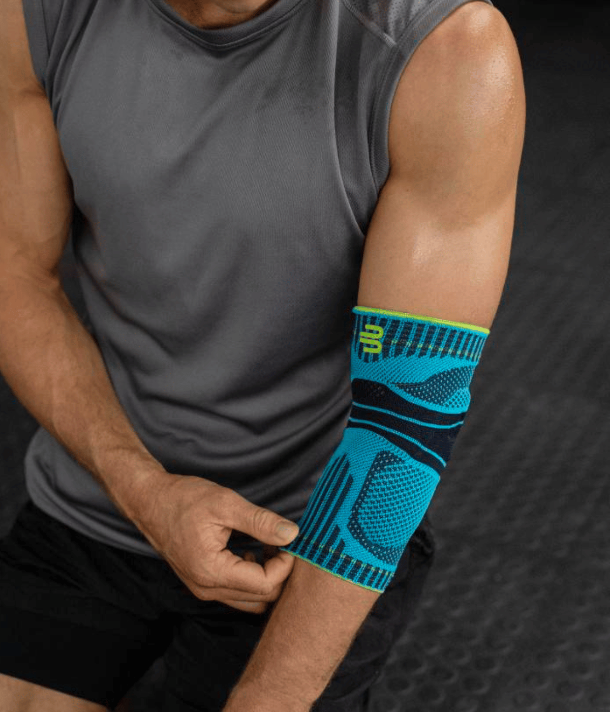 Person wearing a blue elbow support on a dark background