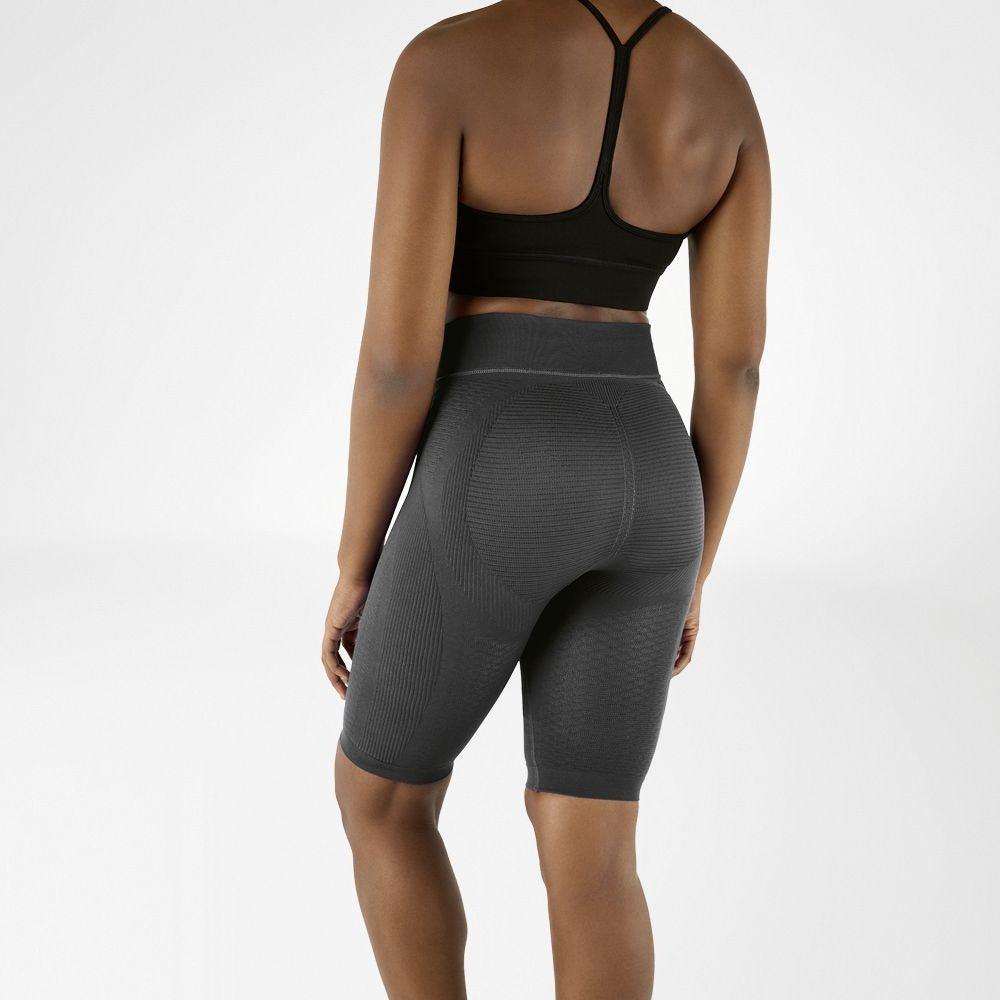 Person wearing grey athletic Bauerfeind Women's sport compression shorts and black sports bra on a white background