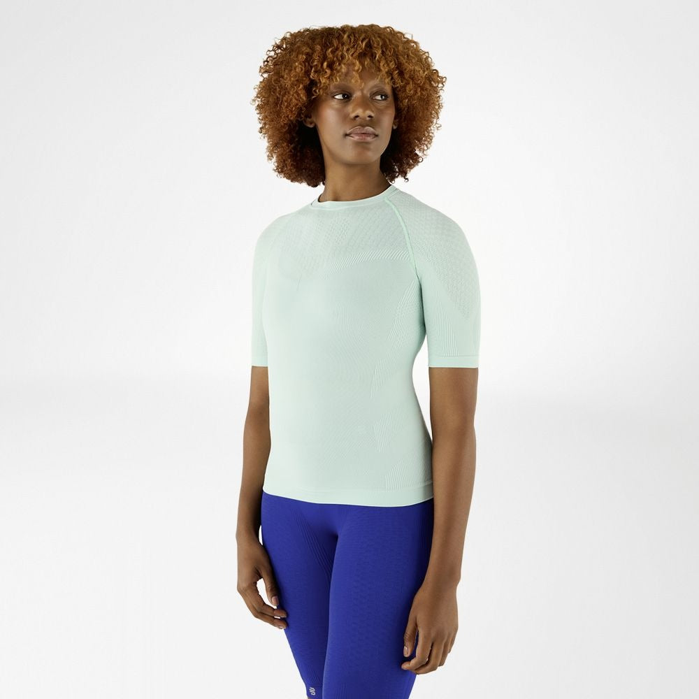 Person wearing minty green athletic Bauerfeind Women's Sports Compression Short Sleeve Shirt and blue Bauerfeind Women's sport compression Leggings on a white background