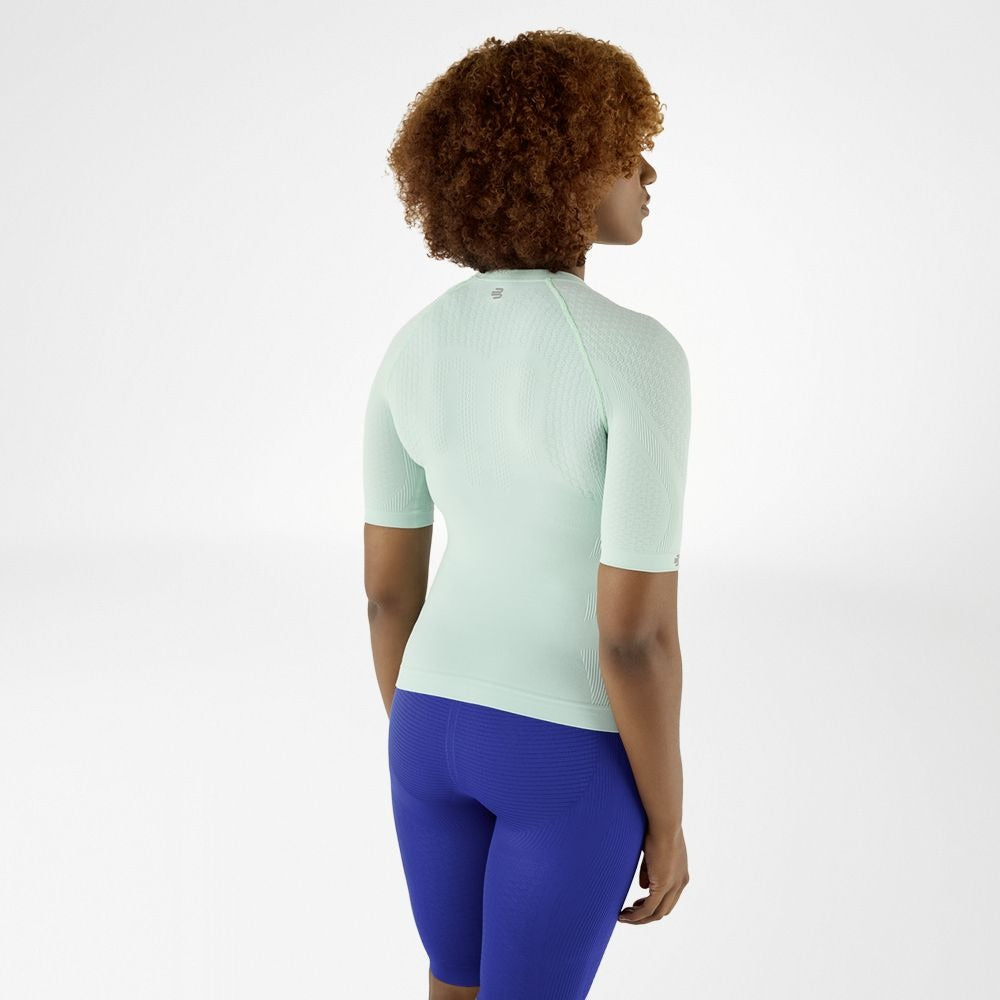 Person wearing minty green athletic Bauerfeind Women's Sports Compression Short Sleeve Shirt and blue Bauerfeind Women's sport compression shorts on a white background