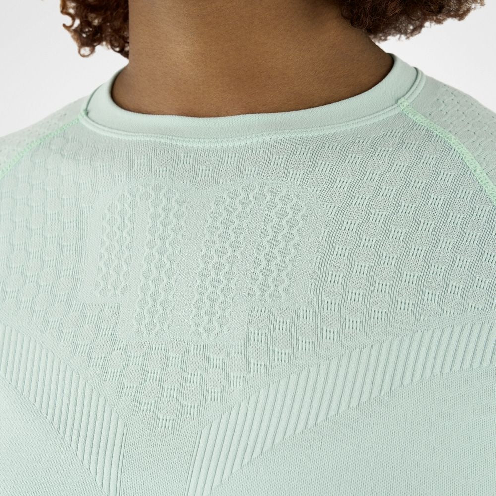 Close-up of a Person wearing minty green athletic Bauerfeind Women's Sports Compression Short Sleeve Shirt and blue Bauerfeind Women's sport compression shorts on a white background