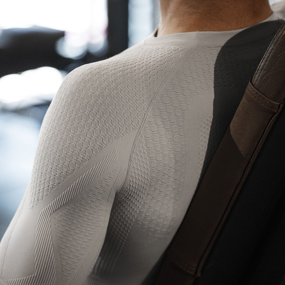 Close-up of the texture on silver Bauerfeind men's sport compression long-sleeve shirt on a blurred indoor background